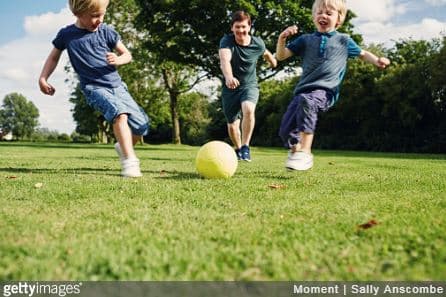Groupe d'enfants qui jouent au ballon de foot dans le jardin