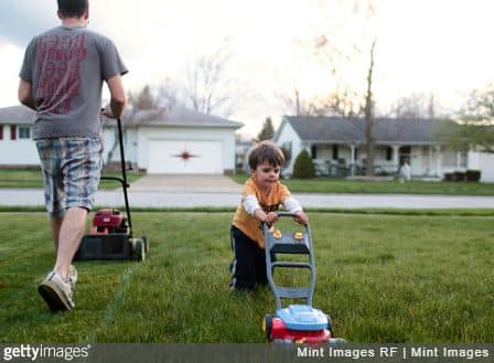 Un papa et son fils qui tondent la pelouse de leur jardin